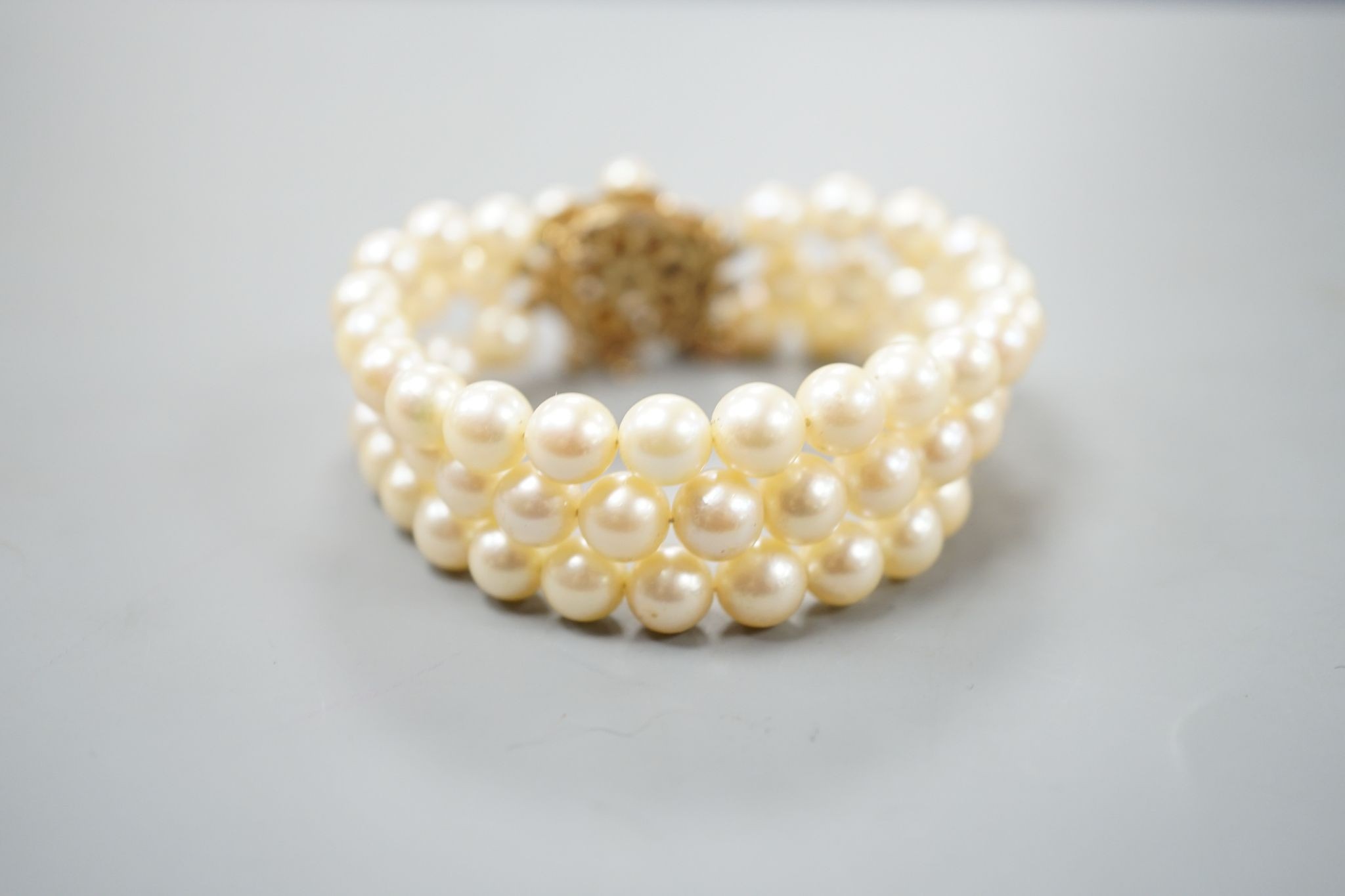 A triple strand cultured pearl bracelet, with yellow metal and cultured pearl cluster set clasp, approx. 16cm.